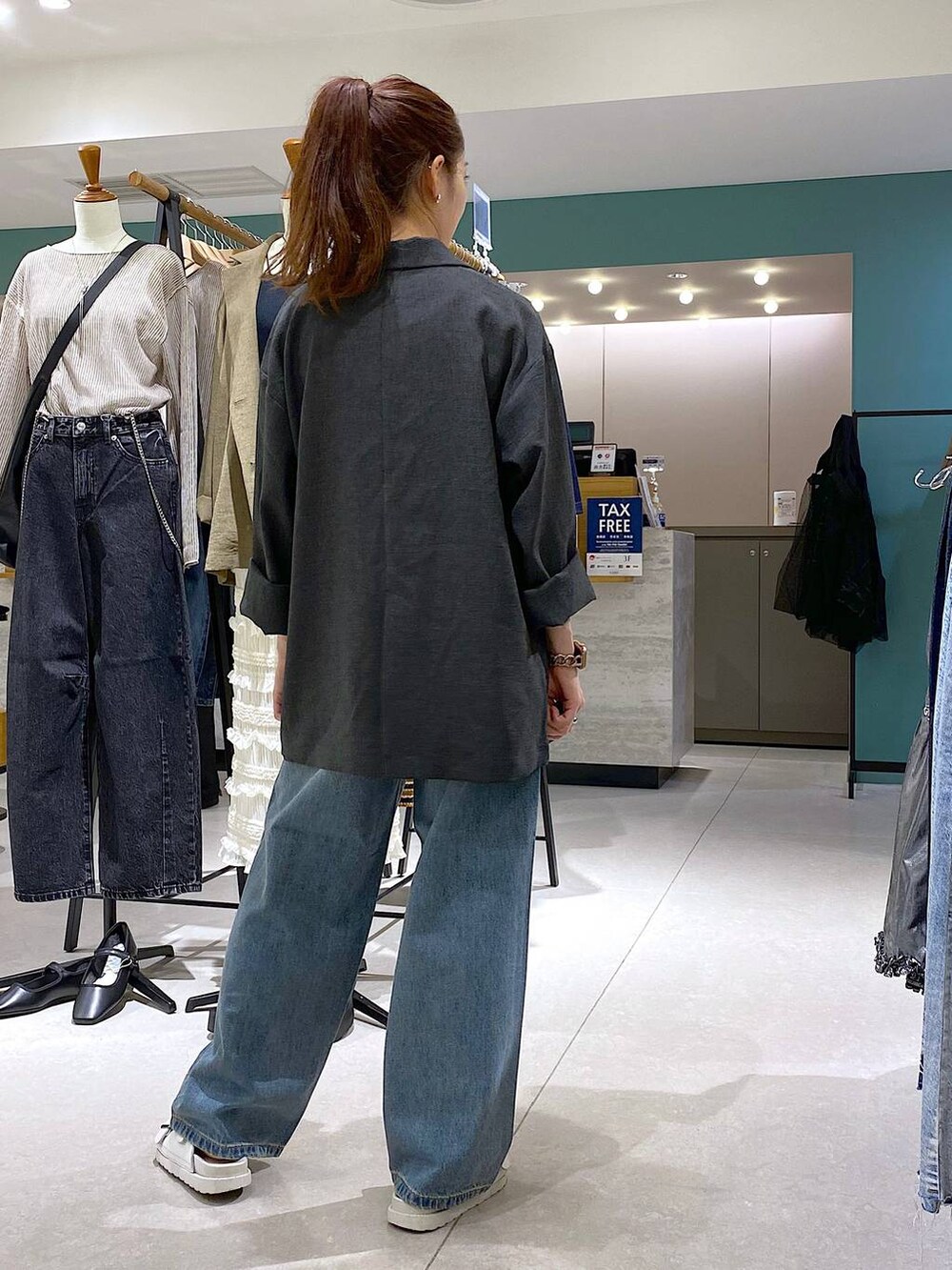 ブルー系のデニムパンツ、グレー系のテーラードジャケット、ホワイト系のサンダルを着用したレディースの秋コーディネートの3枚目の写真