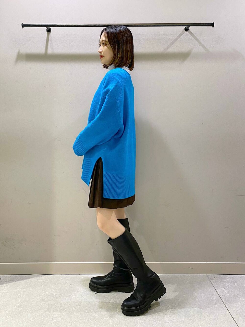 ブラウン系のスカート、ブルー系のニット/セーター、ブラック系のブーツを着用したレディースの秋コーディネートの4枚目の写真