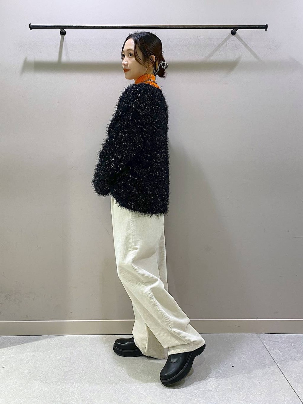 オレンジ系のニット/セーター、ブラック系のブーツ、ホワイト系のその他パンツを着用したレディースの秋コーディネートの2枚目の写真