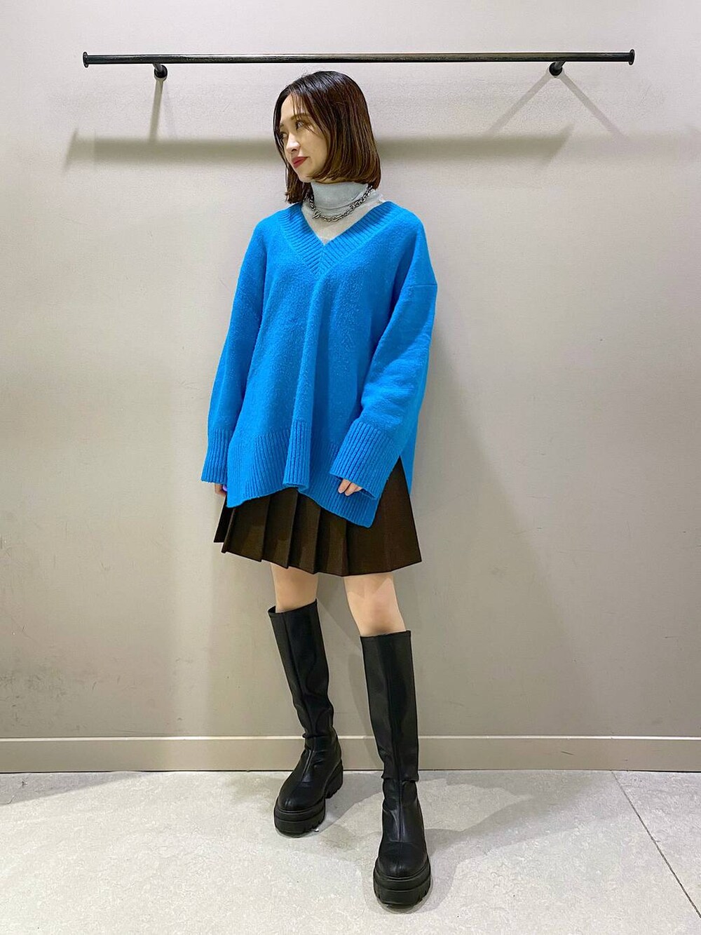 ブラウン系のスカート、ブルー系のニット/セーター、ブラック系のブーツを着用したレディースの秋コーディネートの5枚目の写真