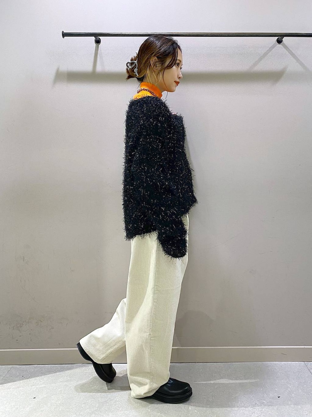 オレンジ系のニット/セーター、ブラック系のブーツ、ホワイト系のその他パンツを着用したレディースの秋コーディネートの4枚目の写真