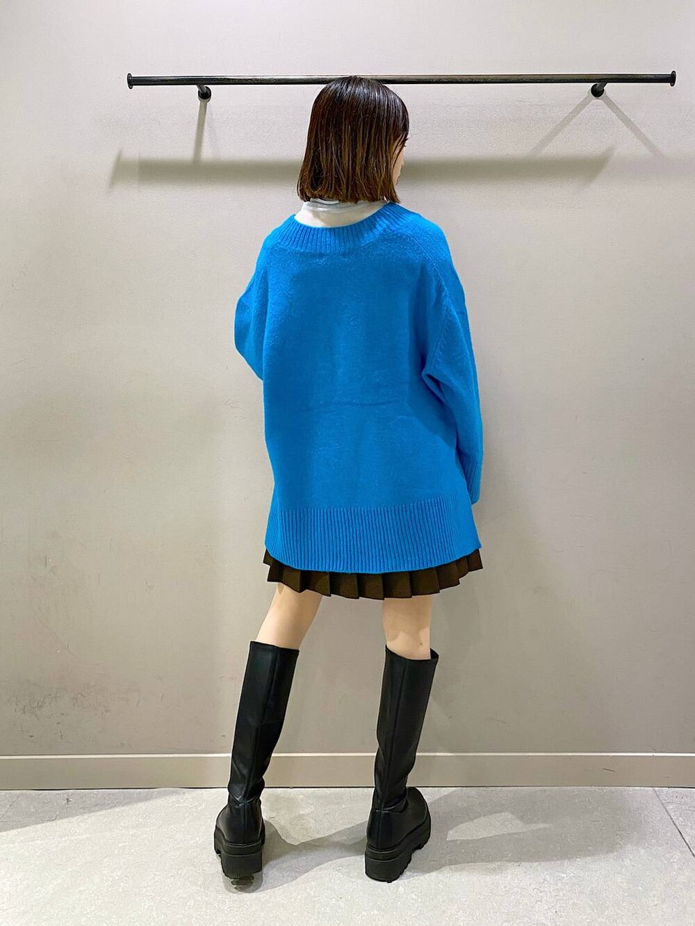 ブラウン系のスカート、ブルー系のニット/セーター、ブラック系のブーツを着用したレディースの秋コーディネートの3枚目の写真