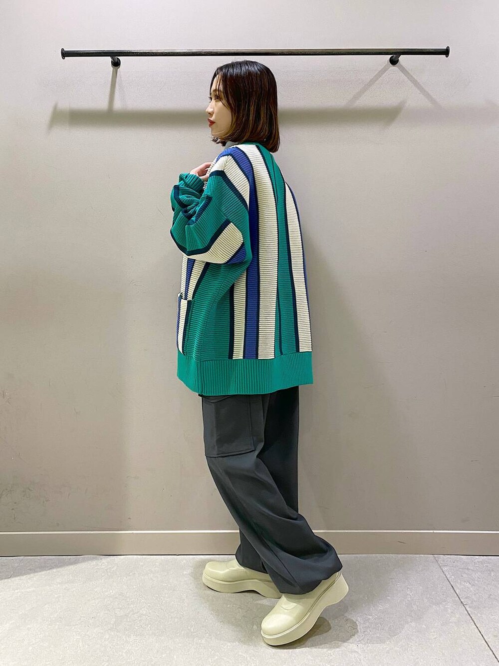 グリーン系のニット/セーター、ホワイト系のブーツ、シルバー系のTシャツ/カットソーを着用したレディースの秋コーディネートの2枚目の写真