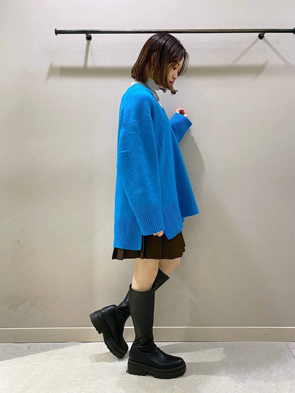 ブラウン系のスカート、ブルー系のニット/セーター、ブラック系のブーツを着用したレディースの秋コーディネートの2枚目の写真