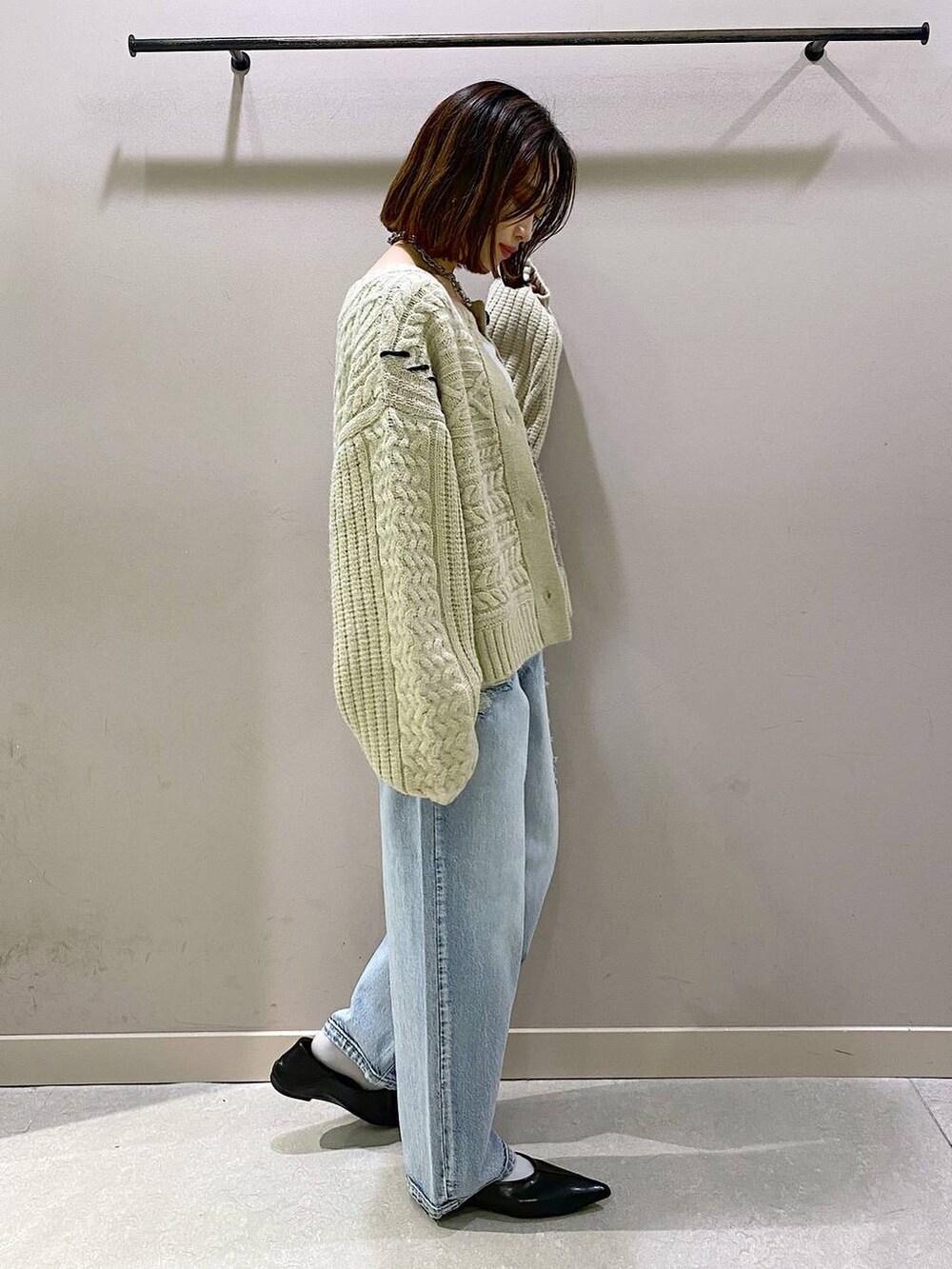 ホワイト系のキャミソール、ブルー系のデニムパンツ、ブラック系のパンプスを着用したレディースの秋コーディネートの2枚目の写真