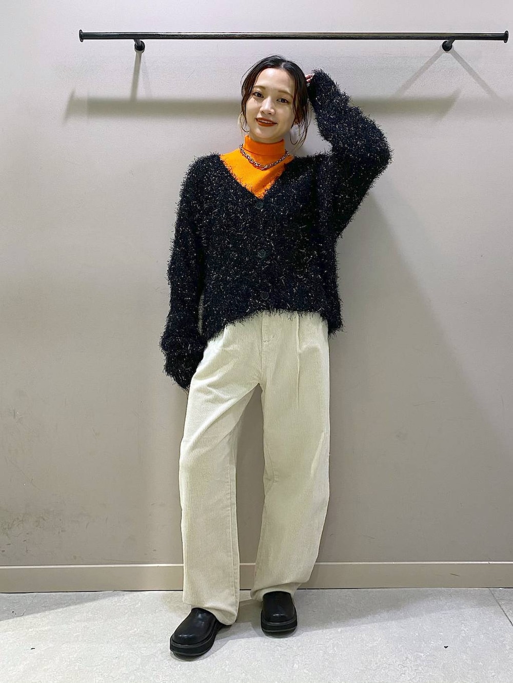 オレンジ系のニット/セーター、ブラック系のブーツ、ホワイト系のその他パンツを着用したレディースの秋コーディネートの5枚目の写真