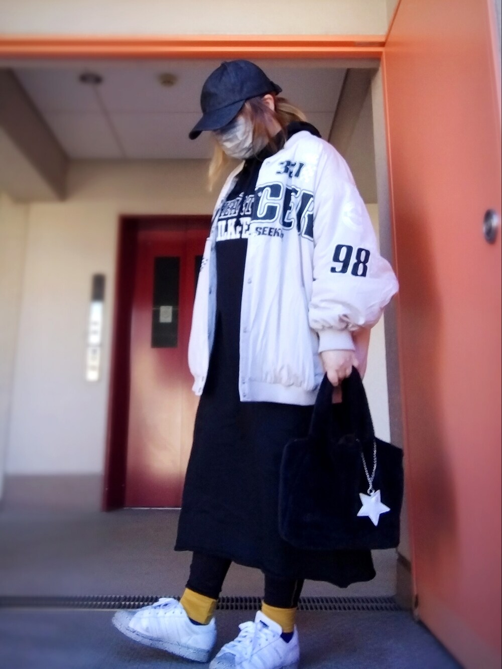 ベージュ系のMA-1、ブラック系のワンピース、ブラック系のトートバッグを着用したレディースの冬コーディネートの2枚目の写真