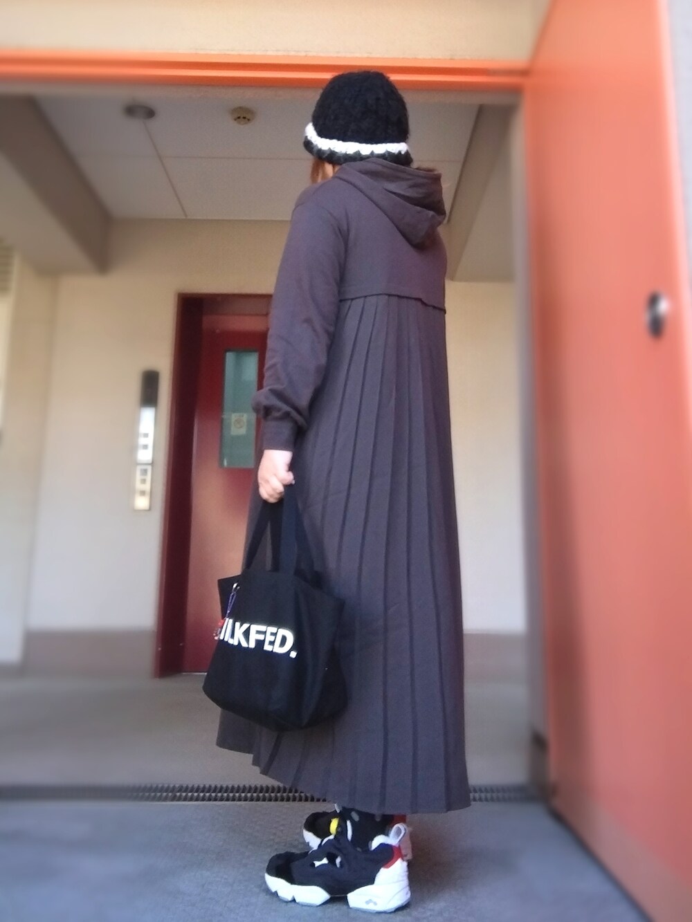 グレー系のワンピース、ブラック系のトートバッグ、ブラック系のスニーカーを着用したレディースの秋コーディネートの2枚目の写真