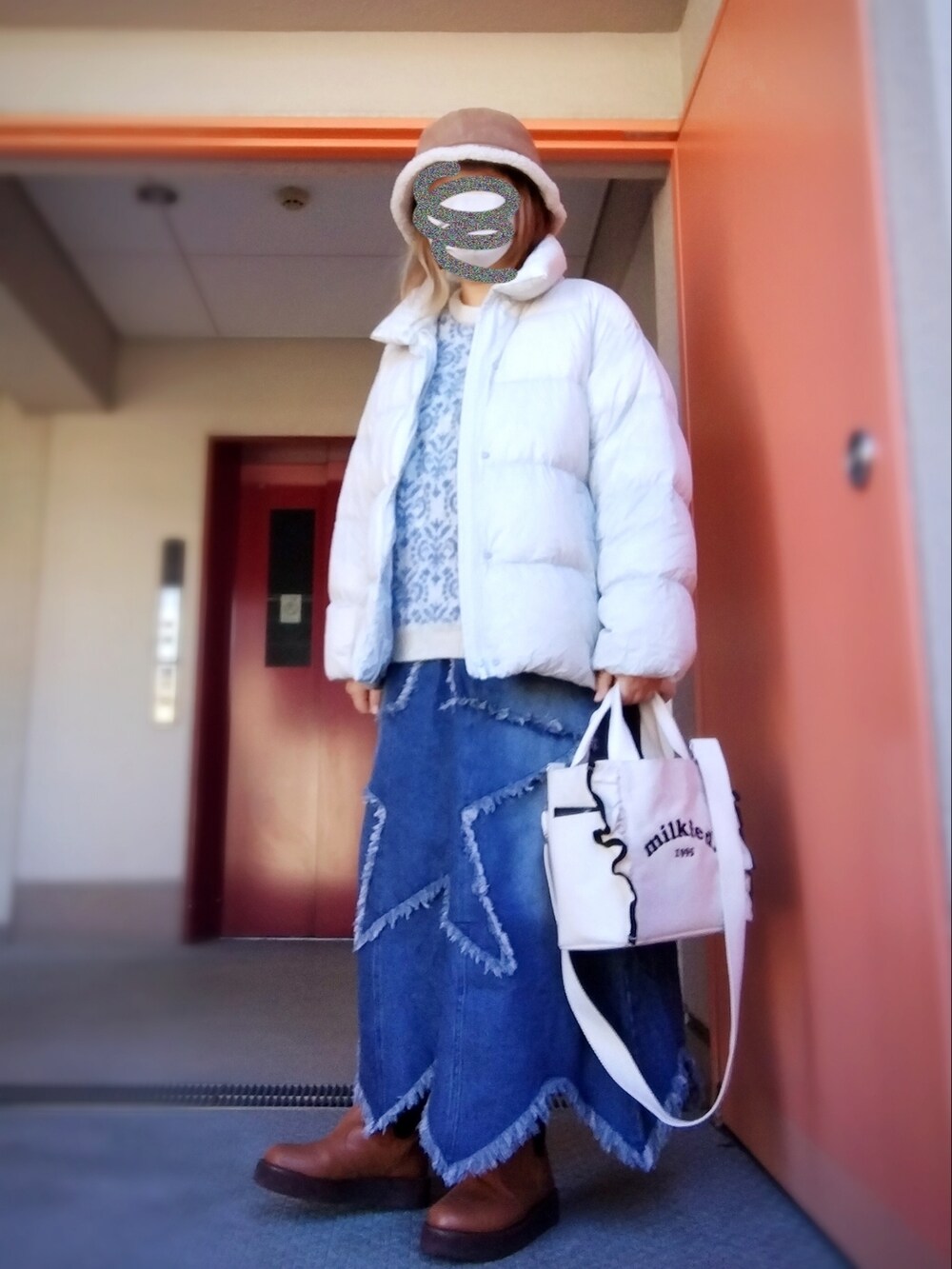 ホワイト系のニット/セーター、ブルー系のデニムスカート、ブラウン系のブーツを着用したレディースの冬コーディネートの2枚目の写真