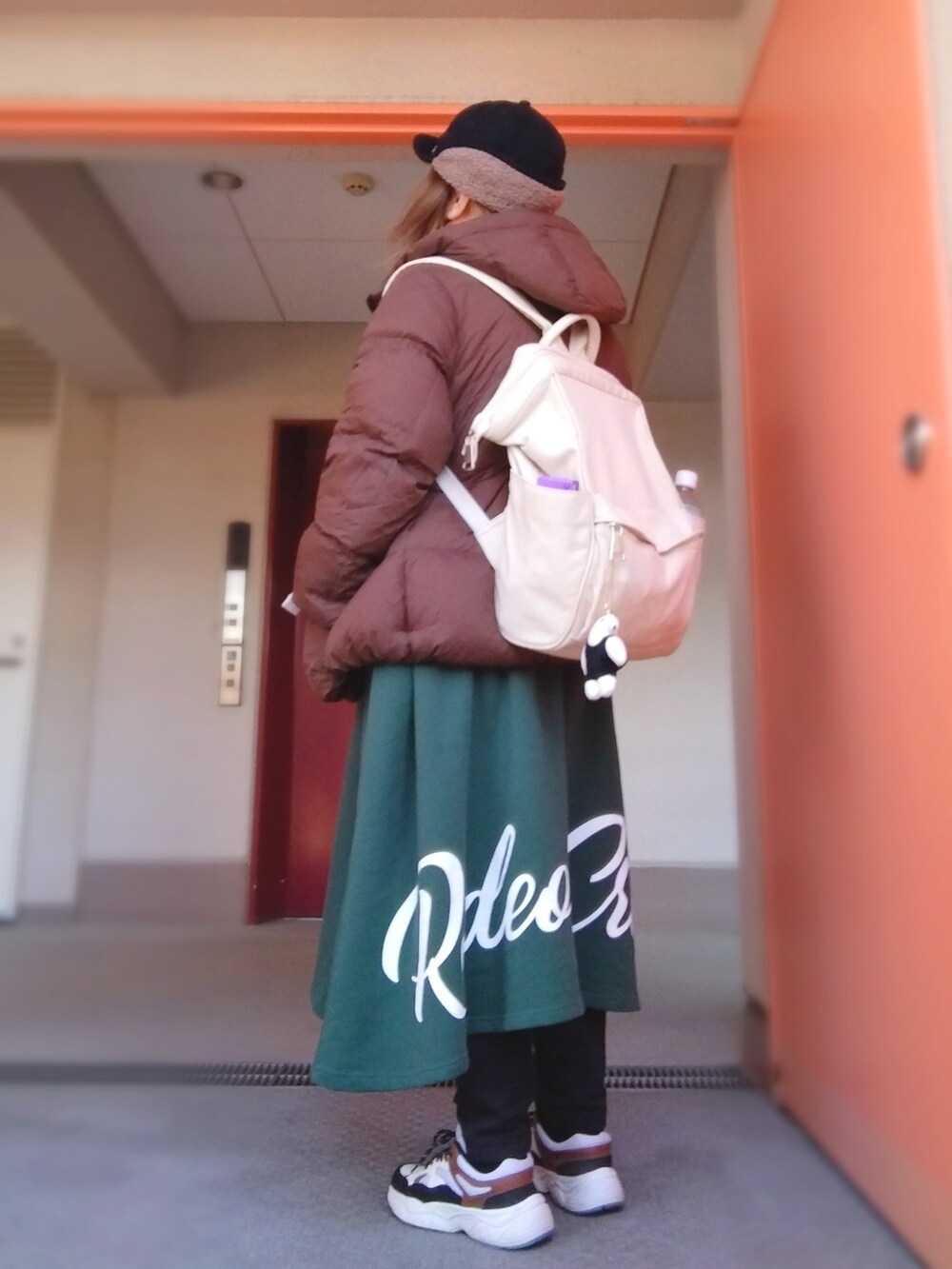 ブラウン系のダウンジャケット/コート、グリーン系のワンピース、ホワイト系のバックパック/リュックを着用したレディースの冬コーディネートの2枚目の写真