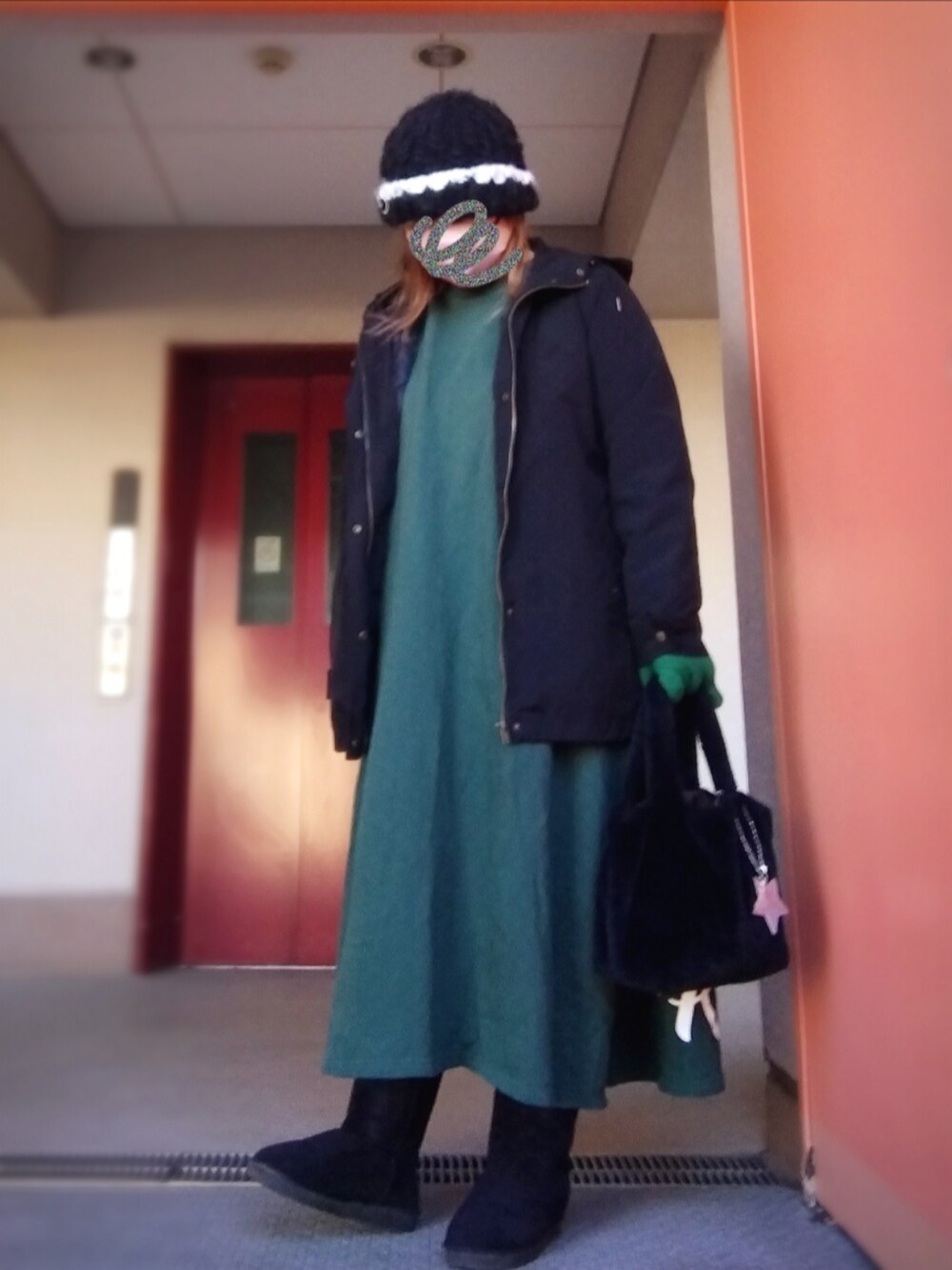 ブラック系のブルゾン、グリーン系のワンピース、ブラック系のトートバッグを着用したレディースの冬コーディネートの2枚目の写真