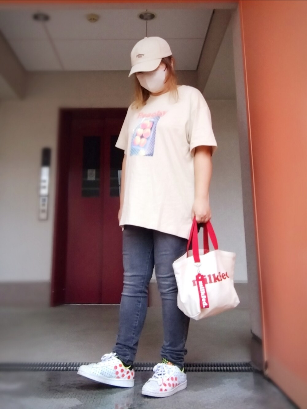 レッド系のマウンテンパーカー、ベージュ系のTシャツ/カットソー、グレー系のデニムパンツを着用したレディースの秋コーディネートの2枚目の写真
