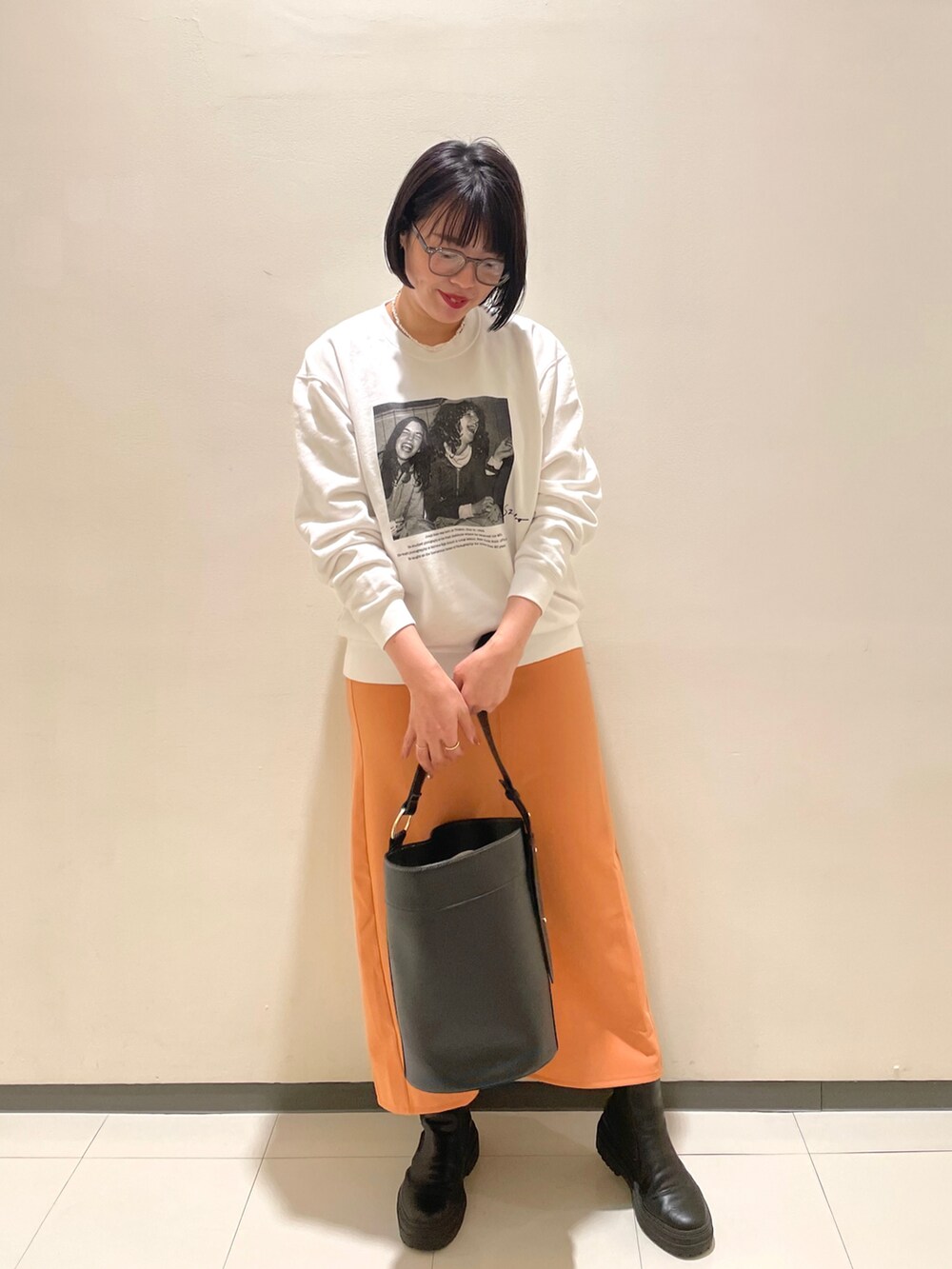 ホワイト系のスウェット、オレンジ系のスカート、グレー系のメガネを着用したレディースの冬コーディネートの2枚目の写真