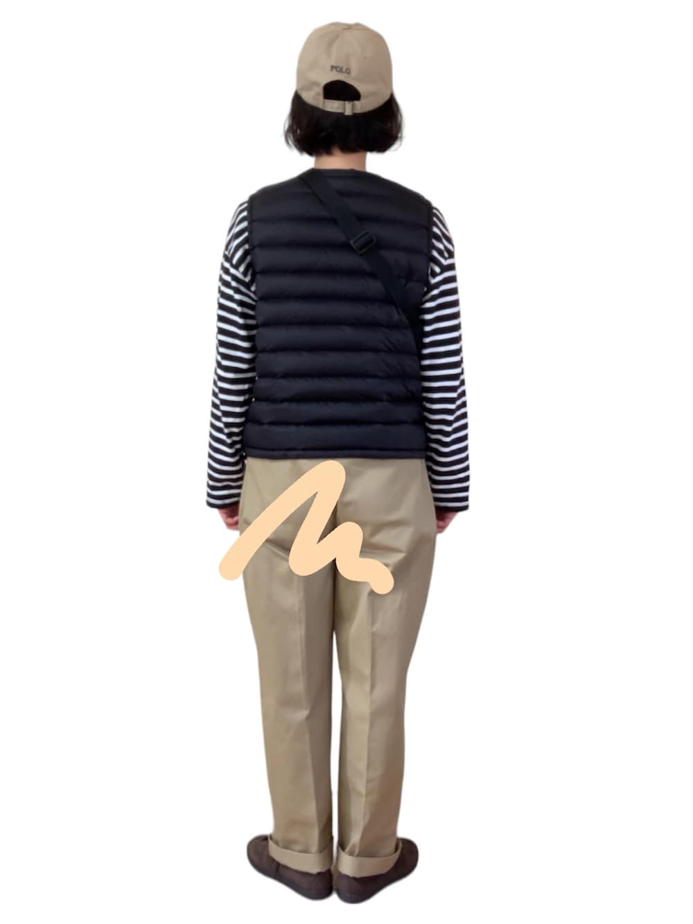 ブラック系のダウンベスト、ベージュ系のチノパンツ、ブラウン系のスニーカーを着用したレディースの春コーディネートの2枚目の写真