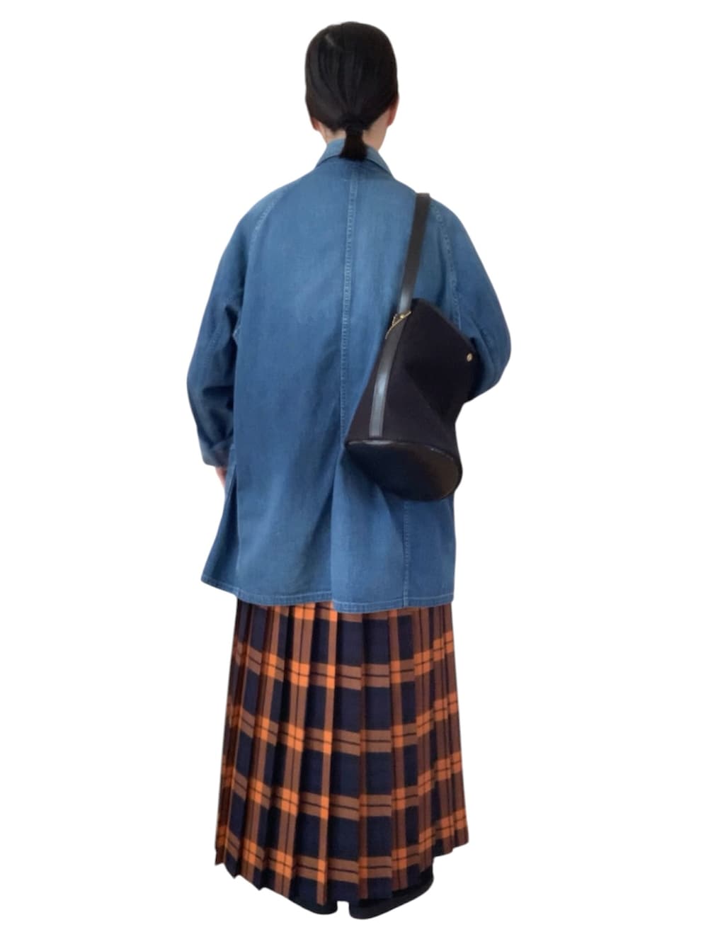 ブルー系のデニムジャケット、ブラック系のダウンベスト、オレンジ系のスカートを着用したレディースの冬コーディネートの3枚目の写真