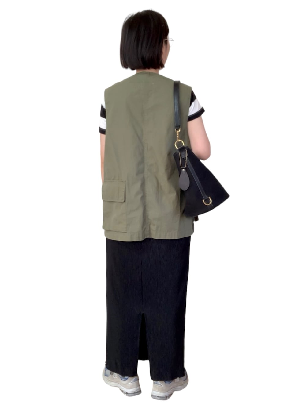 グリーン系のベスト、ブラック系のスカート、グレー系のスニーカーを着用したレディースの夏コーディネートの2枚目の写真