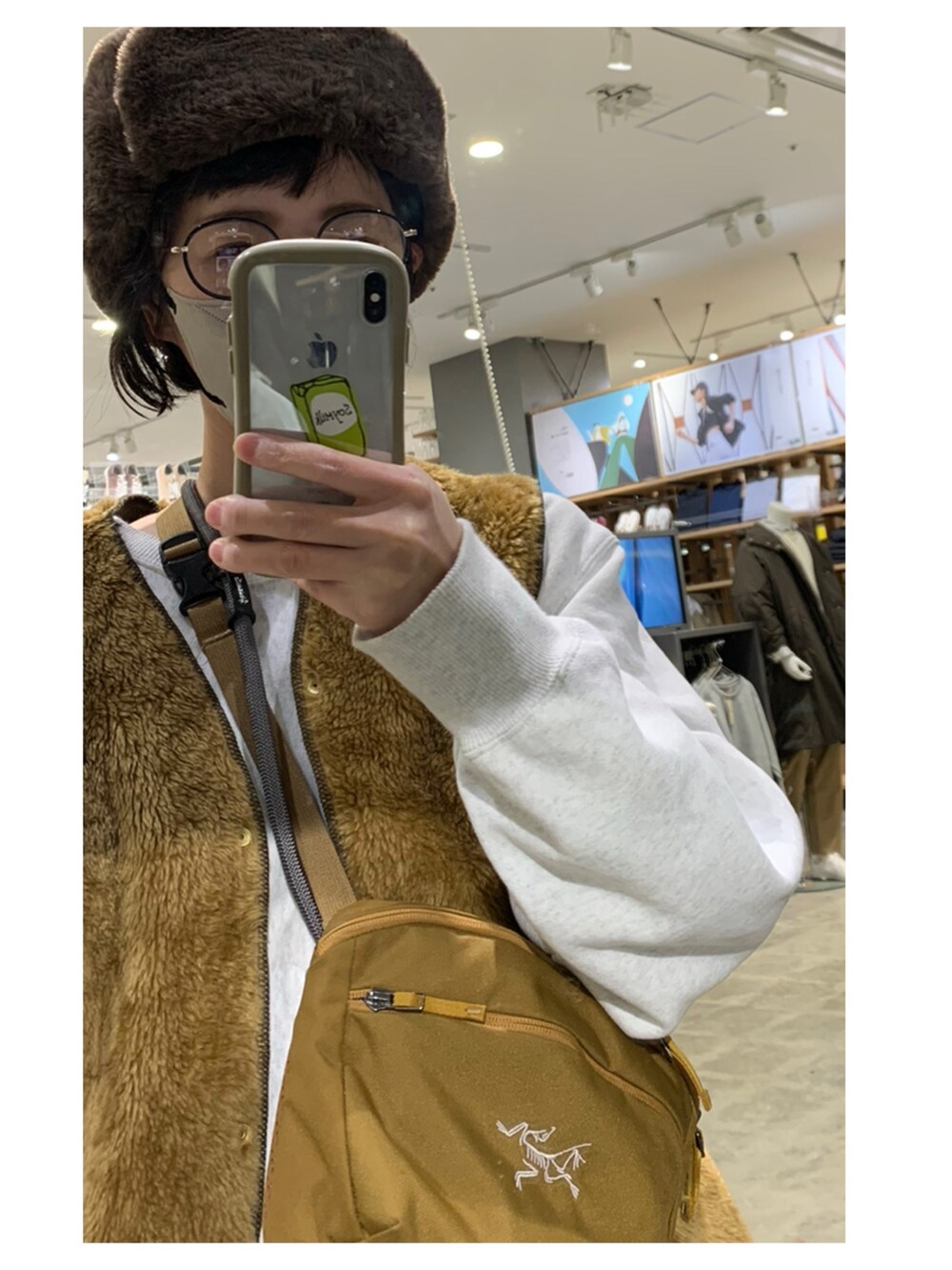 グレー系のスウェット、ブラウン系のベスト、ブラウン系のショルダーバッグを着用したレディースの冬コーディネートの2枚目の写真