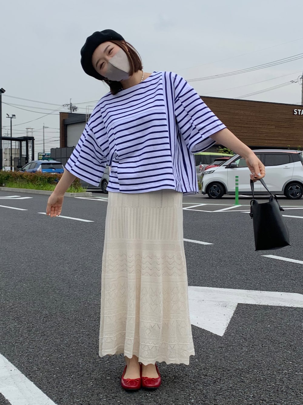 ブラック系のショルダーバッグ、ブラック系のバレエシューズ、ホワイト系のスカートを着用したレディースの夏コーディネートの2枚目の写真