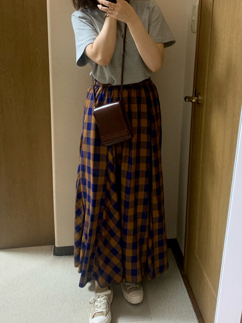 ブラウン系のショルダーバッグ、ベージュ系のスニーカー、ブルー系のスカートを着用したレディースの夏コーディネートの2枚目の写真