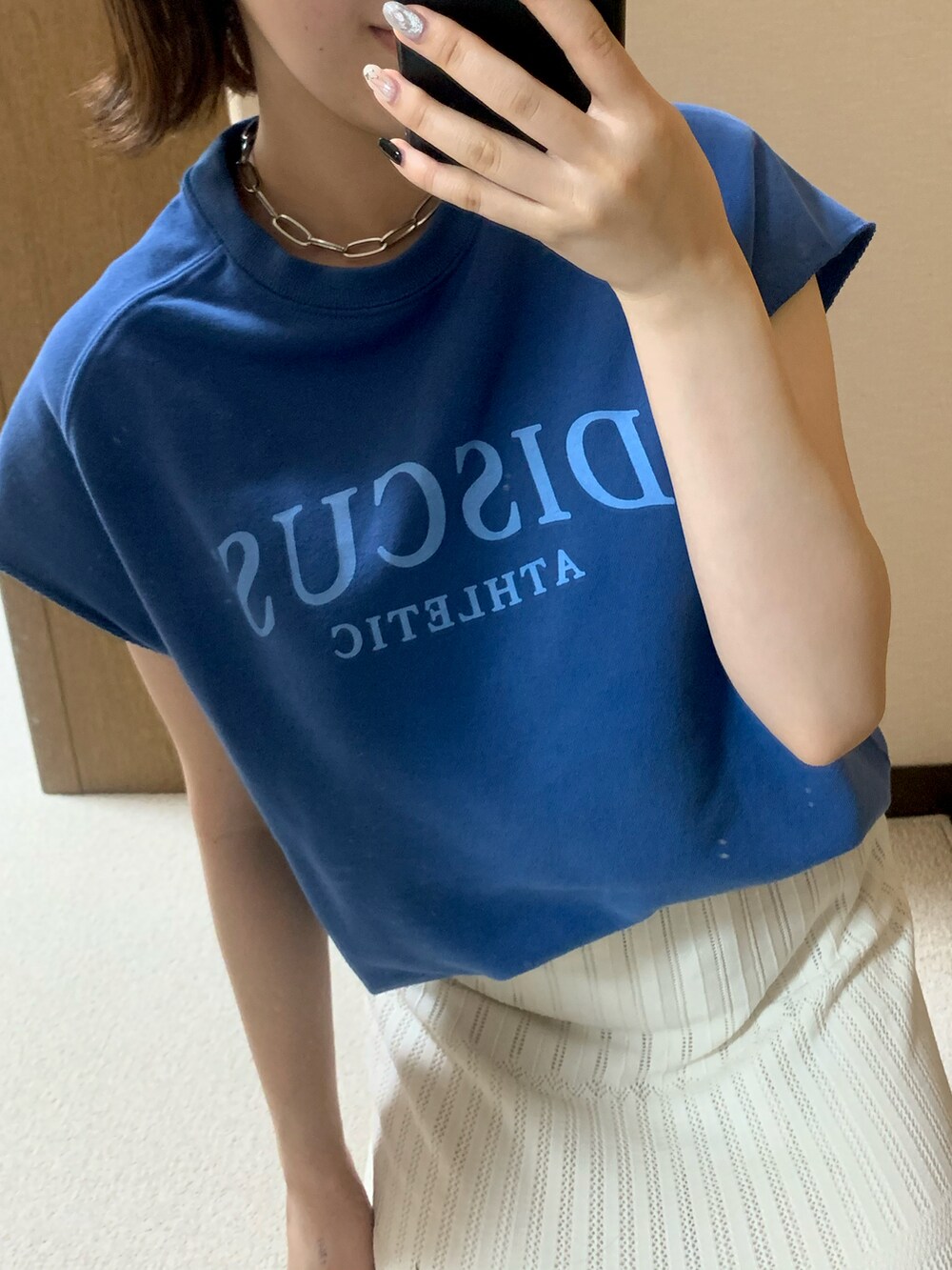 ブラック系のボディバッグ/ウエストポーチ、ホワイト系のスカート、ブラック系のスニーカーを着用したレディースの夏コーディネートの3枚目の写真