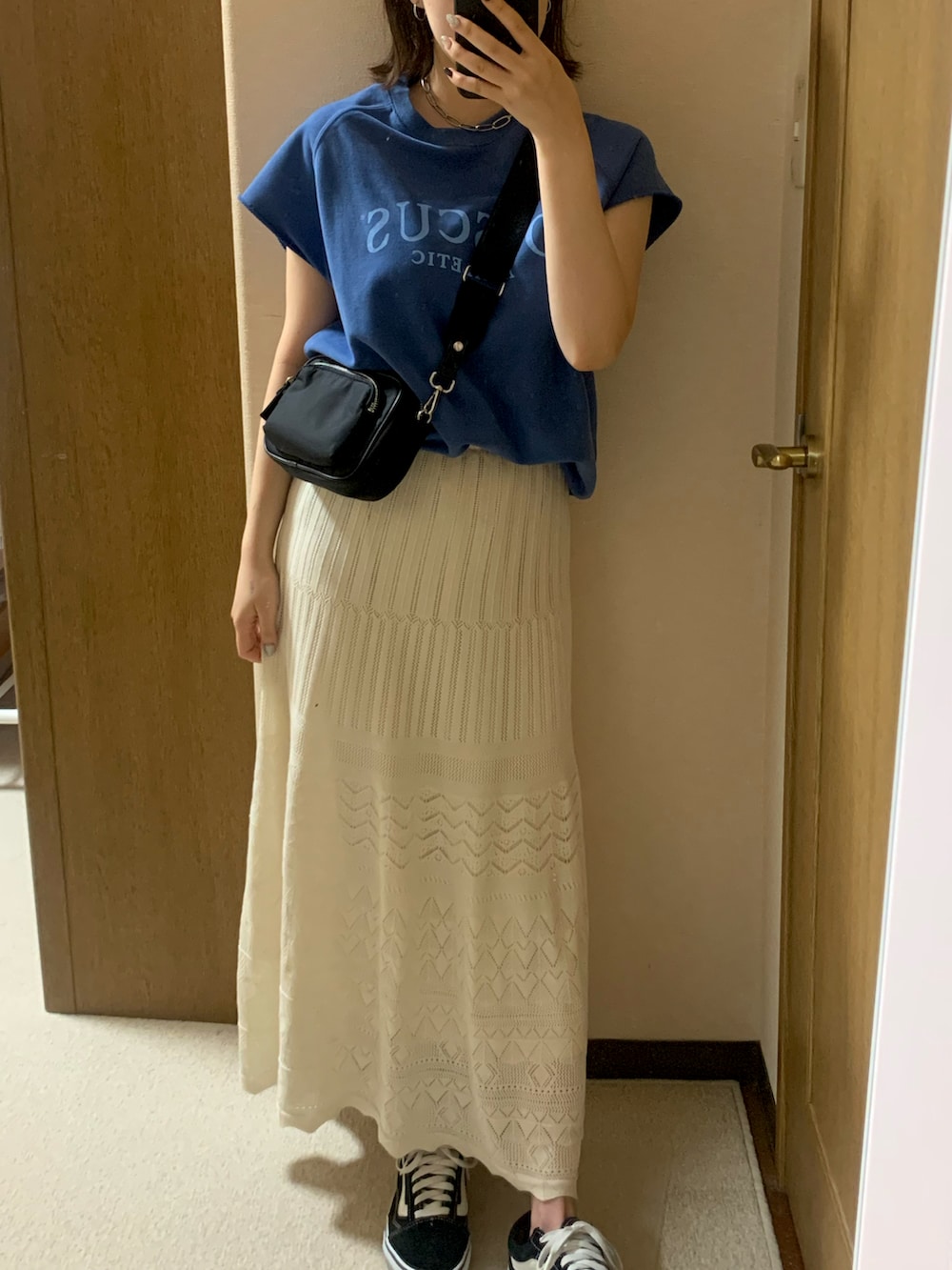 ブラック系のボディバッグ/ウエストポーチ、ホワイト系のスカート、ブラック系のスニーカーを着用したレディースの夏コーディネートの2枚目の写真