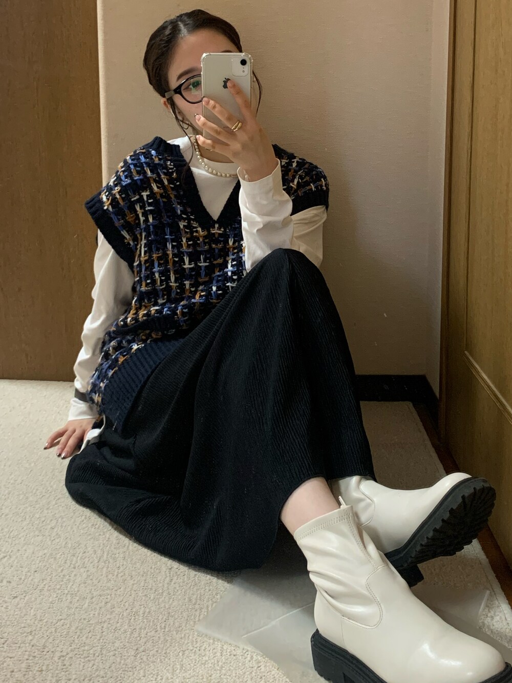 ブルー系のベスト、ホワイト系のTシャツ/カットソー、ブラック系のスカートを着用したレディースの秋コーディネートの2枚目の写真