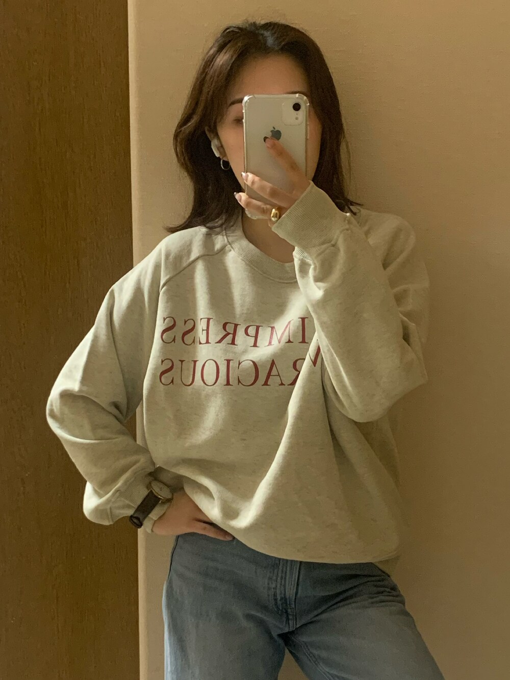 ベージュ系のスニーカー、ブルー系のデニムパンツ、ホワイト系のスウェットを着用したレディースの秋コーディネートの4枚目の写真