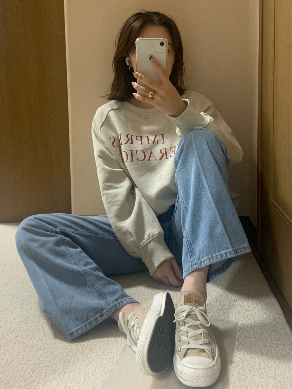 ベージュ系のスニーカー、ブルー系のデニムパンツ、ホワイト系のスウェットを着用したレディースの秋コーディネートの2枚目の写真