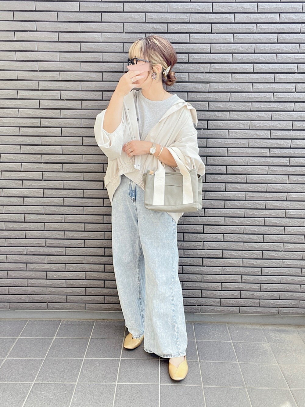 ホワイト系のマウンテンパーカー、グレー系のTシャツ/カットソー、ブルー系のデニムパンツを着用したレディースの春コーディネートの2枚目の写真
