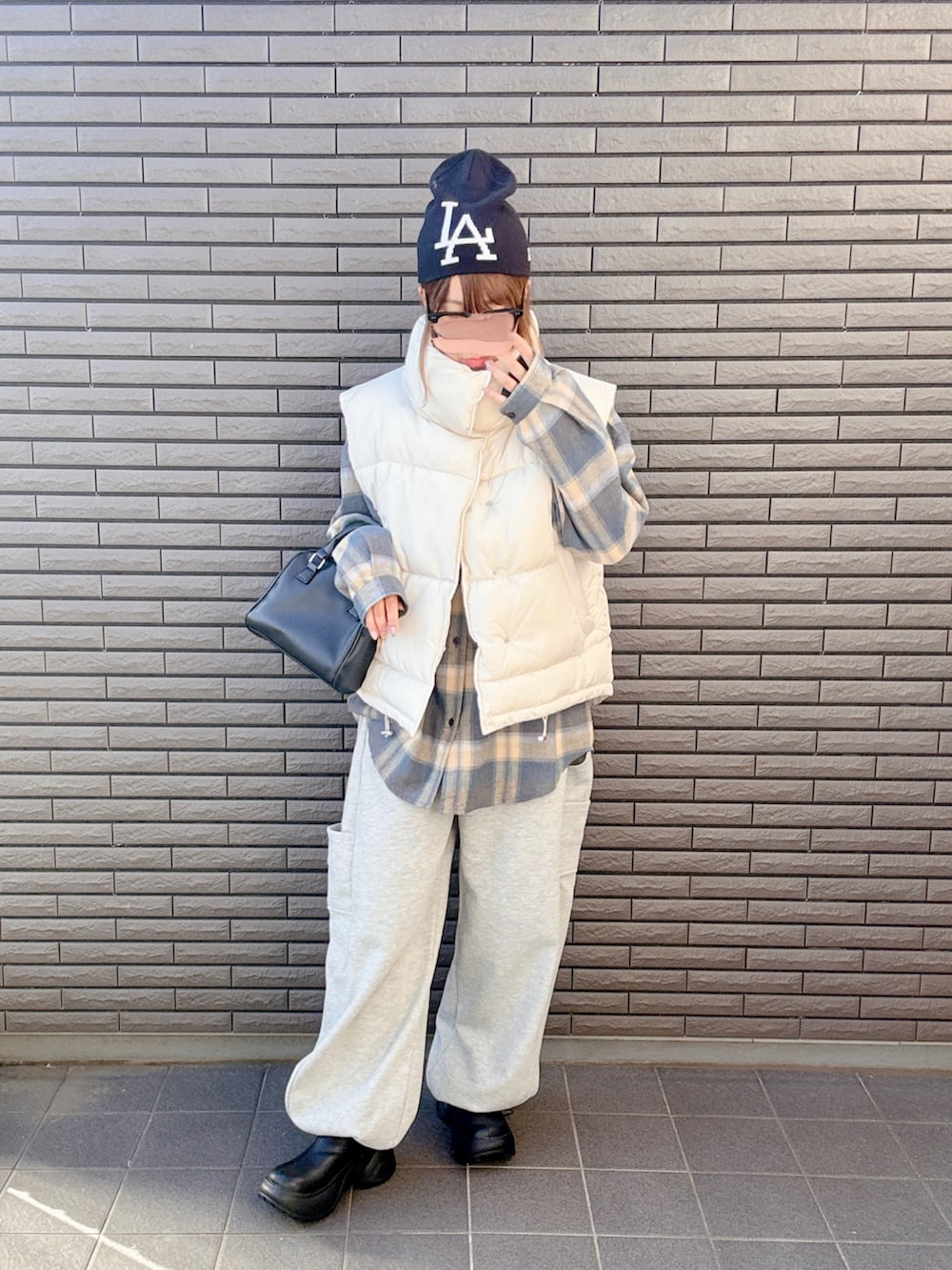 ブラック系のブーツ、ホワイト系のベスト、グレー系のスウェットパンツを着用したレディースの秋コーディネートの2枚目の写真