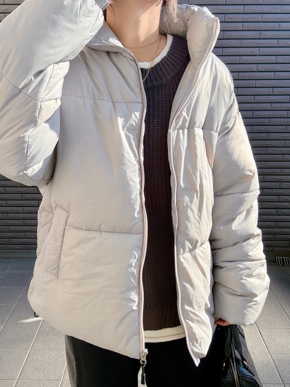 グレー系のニット/セーター、グレー系のダウンジャケット/コート、ブラック系のスウェットパンツを着用したレディースの冬コーディネートの4枚目の写真