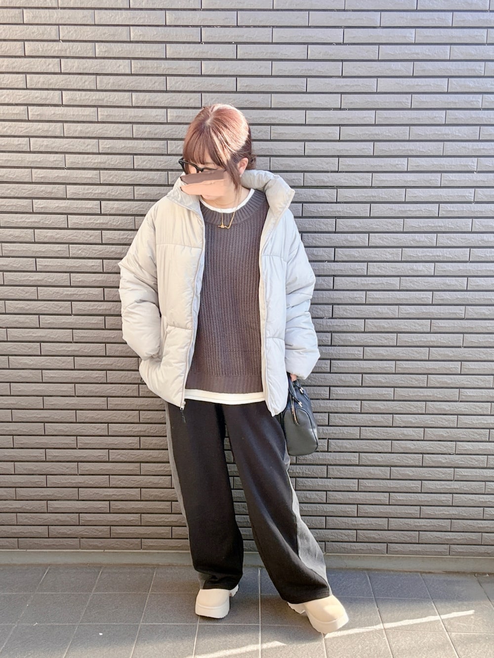 グレー系のニット/セーター、グレー系のダウンジャケット/コート、ブラック系のスウェットパンツを着用したレディースの冬コーディネートの3枚目の写真