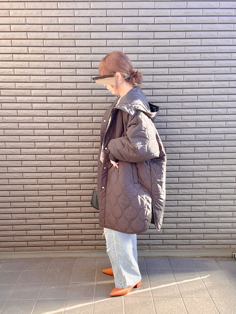 ブラック系のダウンジャケット/コート、ブルー系のニット/セーター、ブルー系のデニムパンツを着用したレディースの冬コーディネートの2枚目の写真