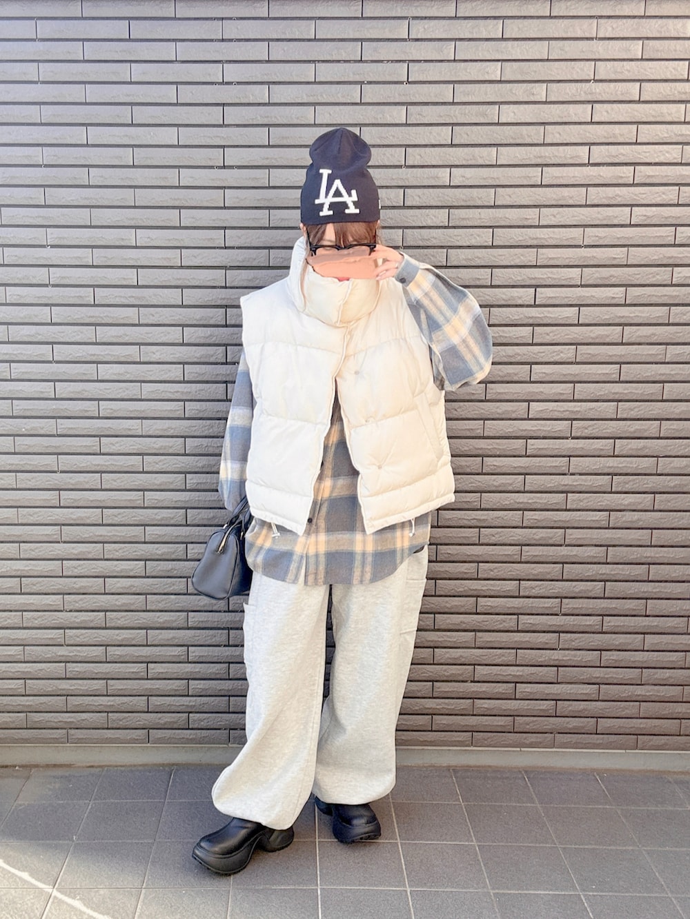 ブラック系のブーツ、ホワイト系のベスト、グレー系のスウェットパンツを着用したレディースの秋コーディネートの3枚目の写真