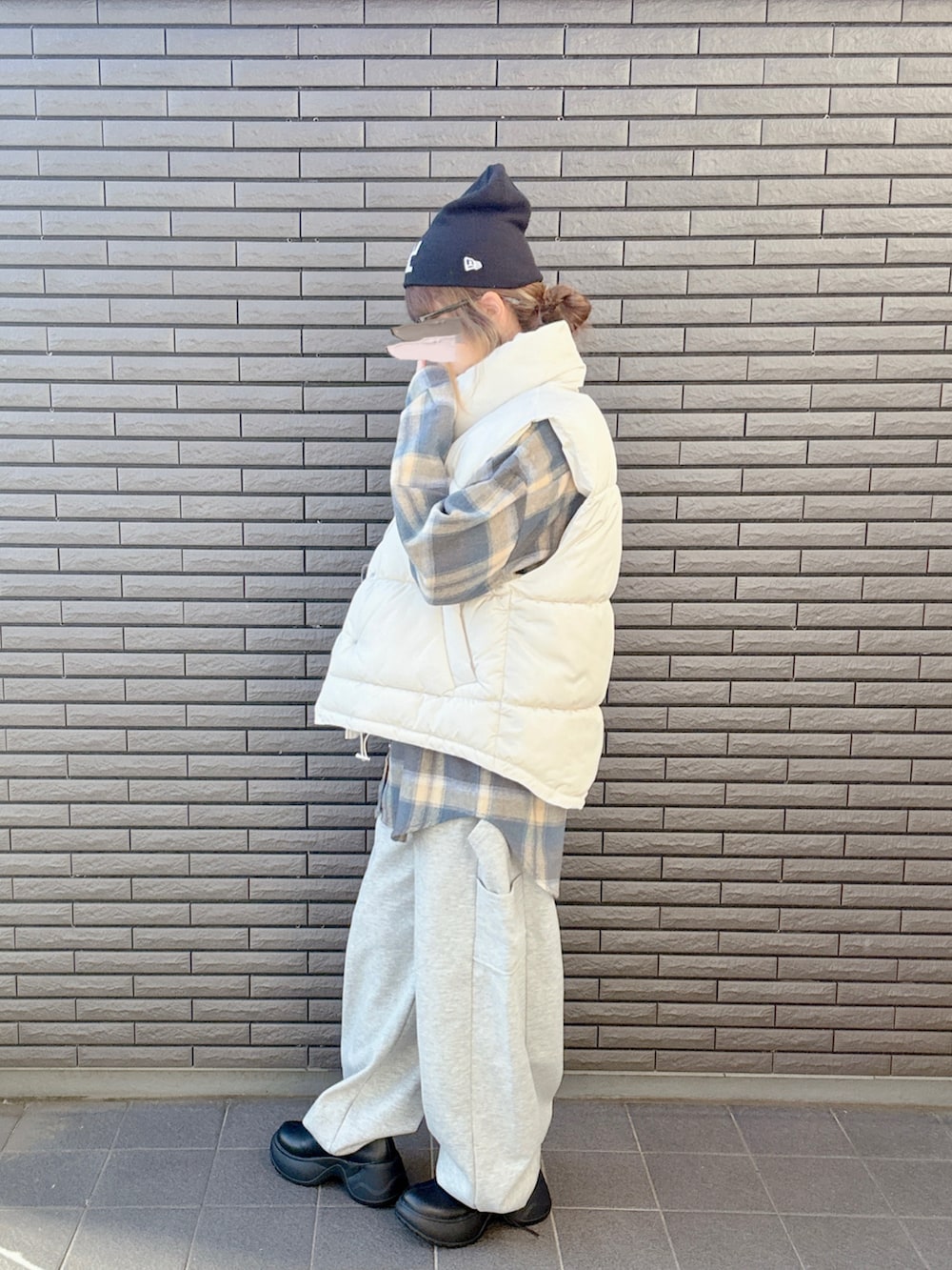 ブラック系のブーツ、ホワイト系のベスト、グレー系のスウェットパンツを着用したレディースの秋コーディネートの4枚目の写真