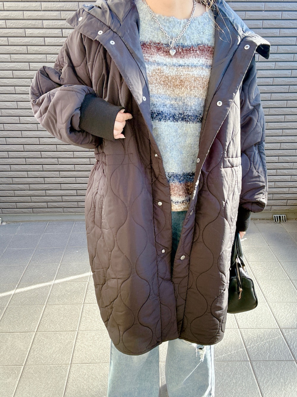 ブラック系のダウンジャケット/コート、ブルー系のニット/セーター、ブルー系のデニムパンツを着用したレディースの冬コーディネートの4枚目の写真