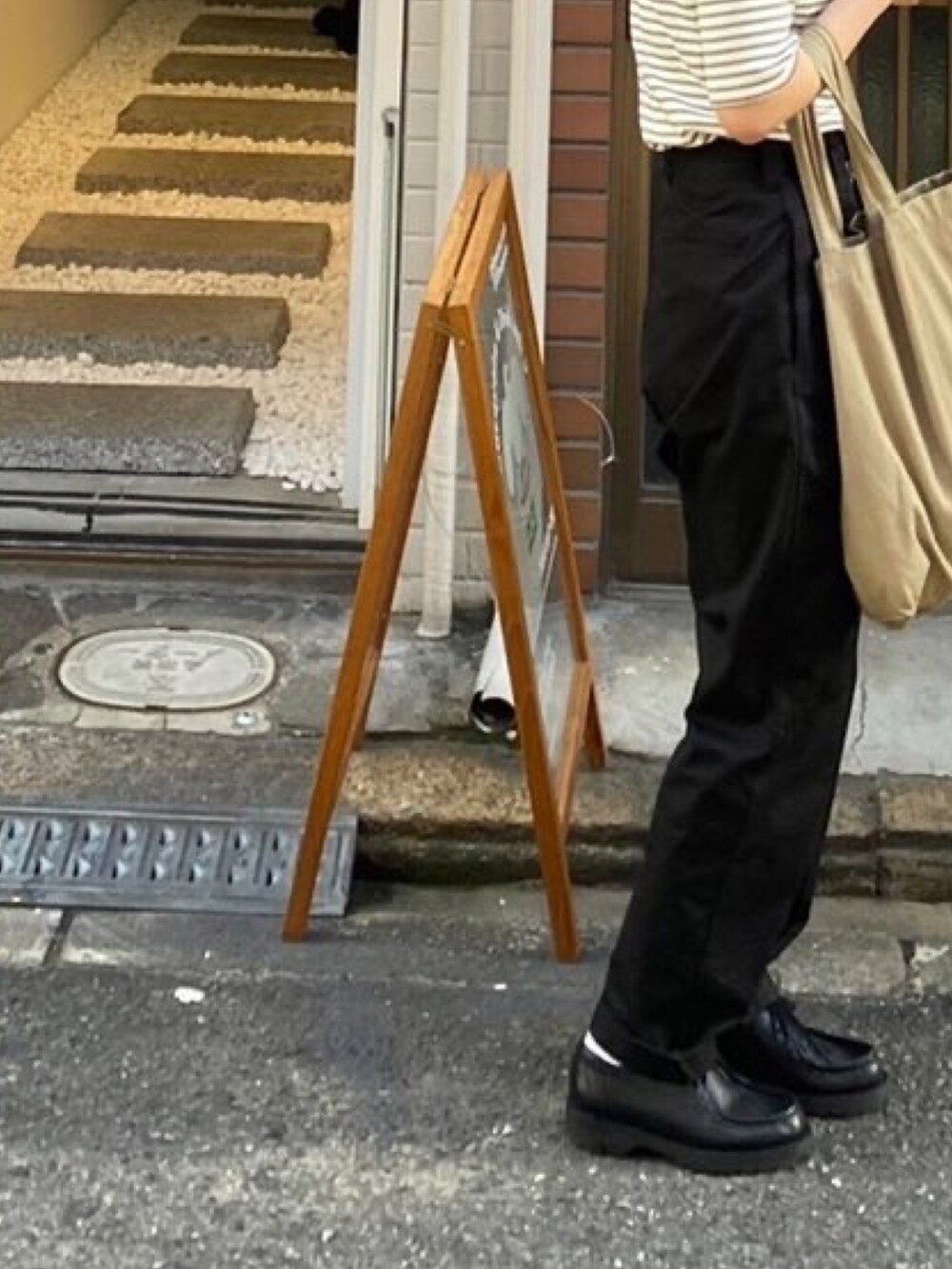 ホワイト系のトップス、ベージュ系のトートバッグ、ブラック系のパンツを着用したレディースの秋コーディネートの2枚目の写真