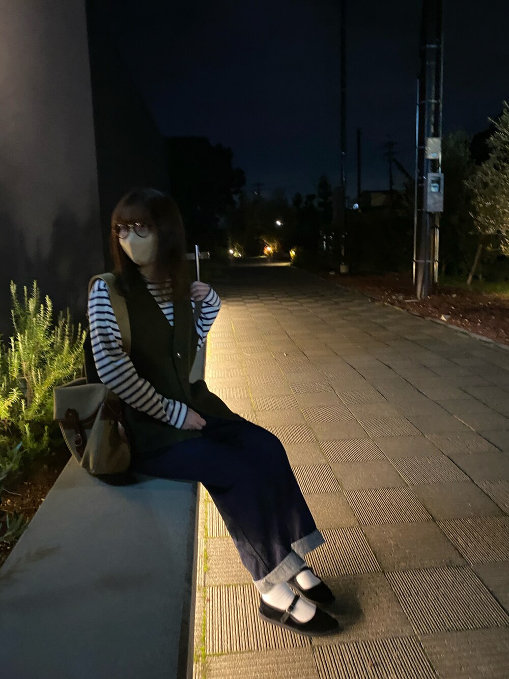 グリーン系のベスト、ブラウン系のショルダーバッグ、ブラック系のデニムパンツを着用したレディースの秋コーディネートの2枚目の写真