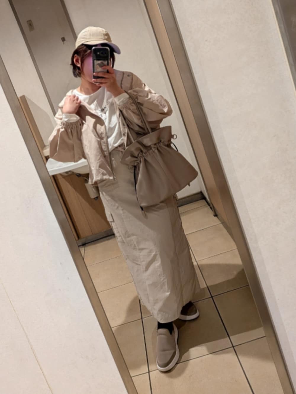 グレー系のマウンテンパーカー、ベージュ系のスカート、ピンク系のハンドバッグを着用したレディースの春コーディネートの2枚目の写真