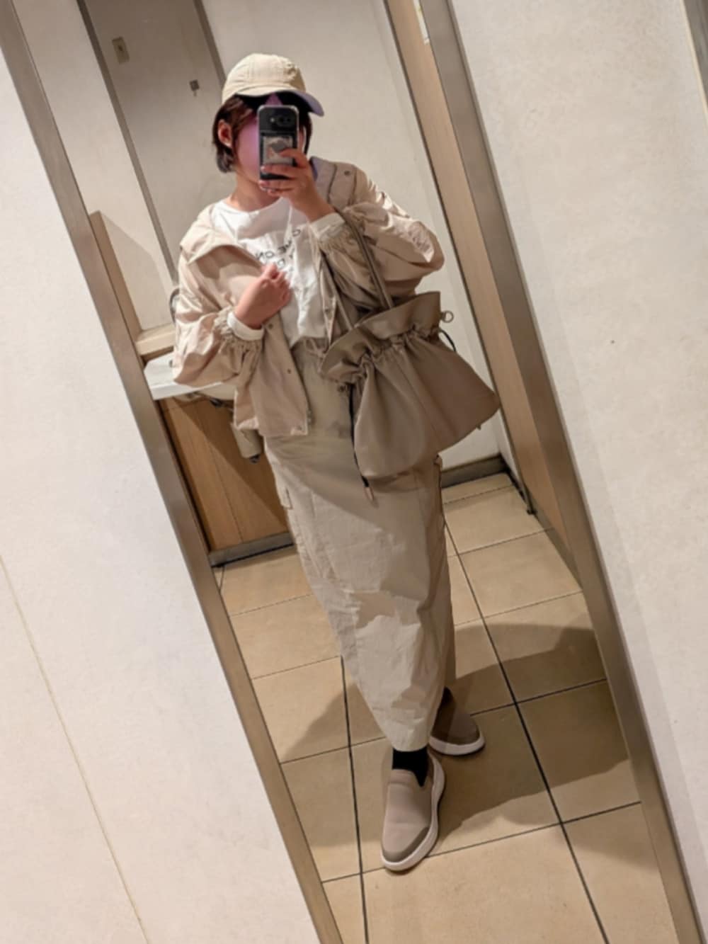 グレー系のマウンテンパーカー、ベージュ系のスカート、ピンク系のハンドバッグを着用したレディースの春コーディネートの3枚目の写真