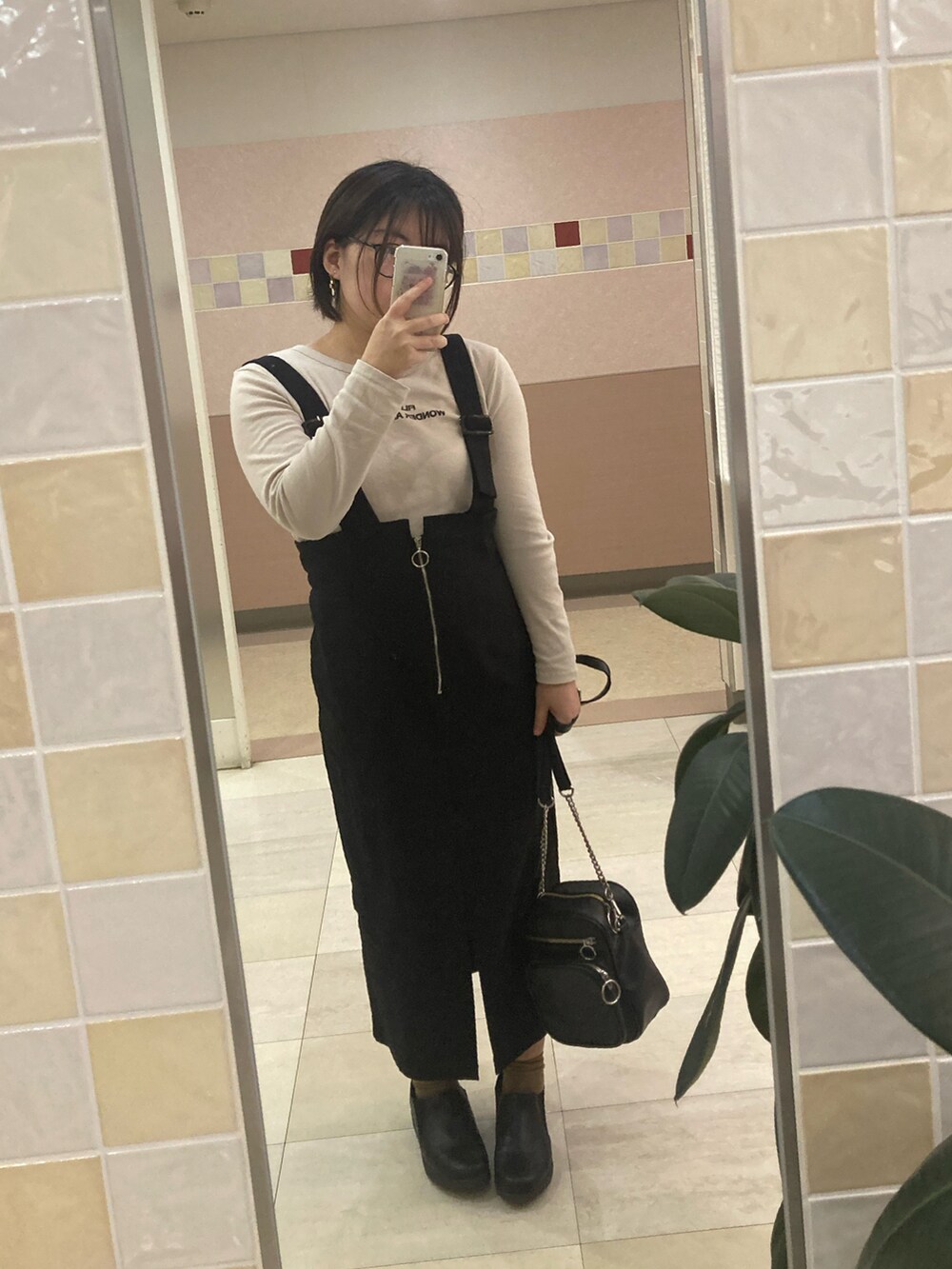 グリーン系のMA-1、ブラック系のジャンパースカート、ブラック系のショルダーバッグを着用したレディースの春コーディネートの2枚目の写真