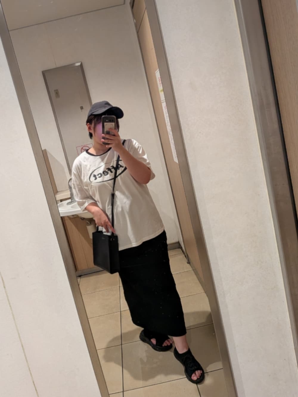 ブラック系のスカート、ホワイト系のTシャツ/カットソー、ブラック系のサンダルを着用したレディースの夏コーディネートの2枚目の写真
