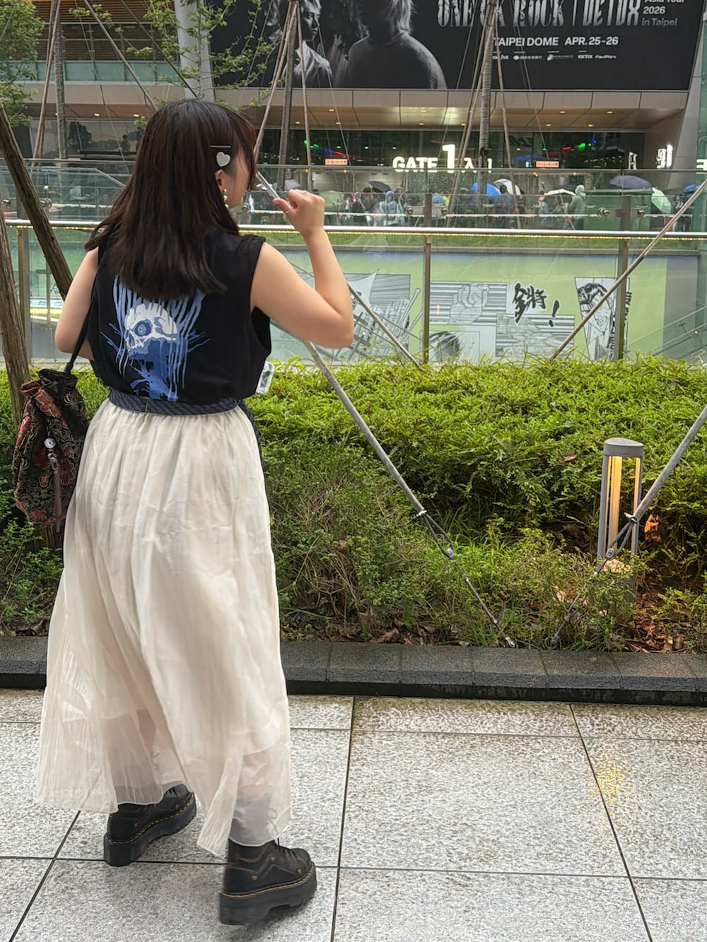 ベージュ系のスカート、ブルー系のネクタイ、ブラック系のトップスを着用したレディースの春コーディネートの3枚目の写真