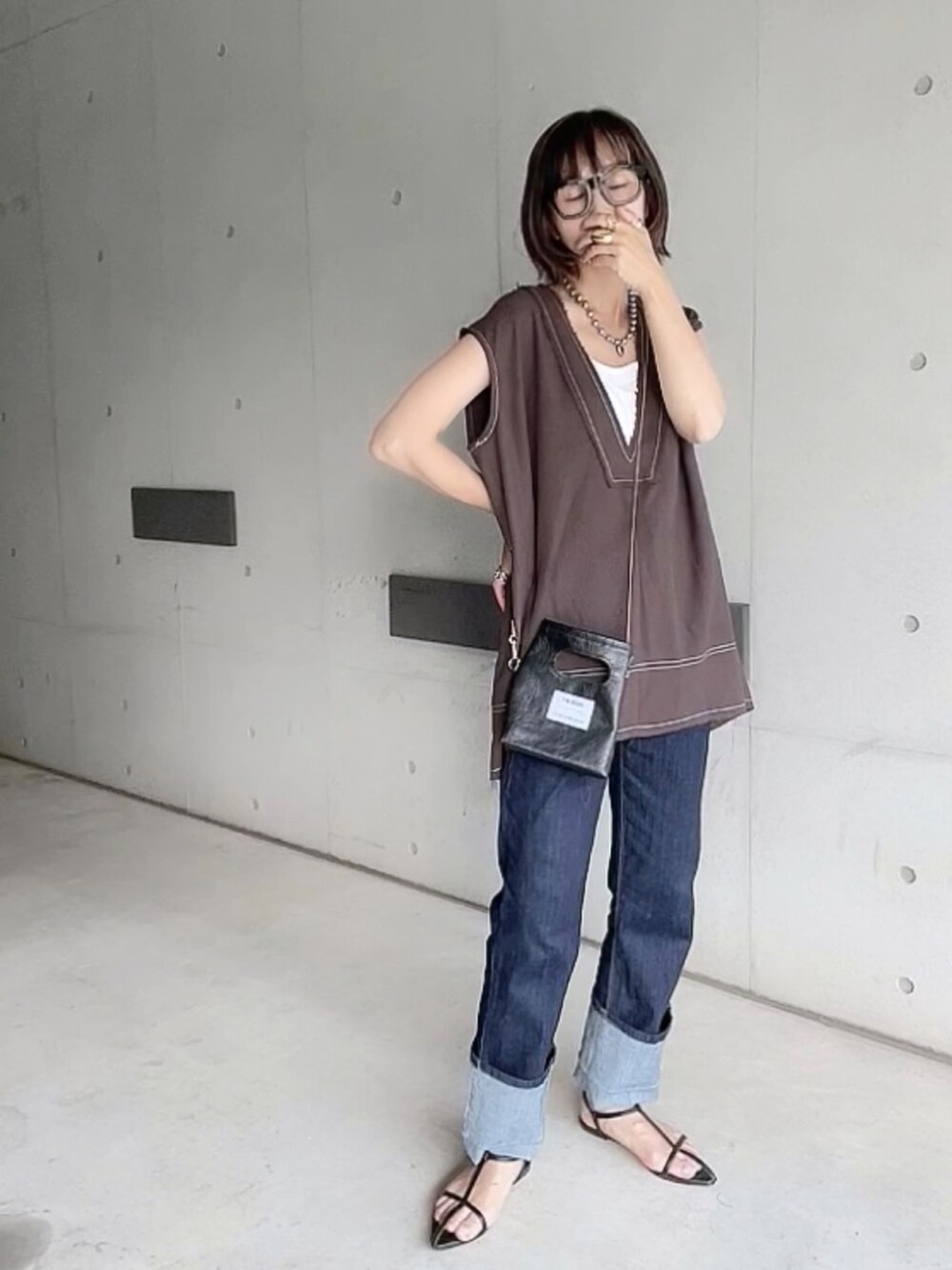 ブラウン系のベスト、ブルー系のデニムパンツ、ブラック系のサンダルを着用したレディースの夏コーディネートの2枚目の写真