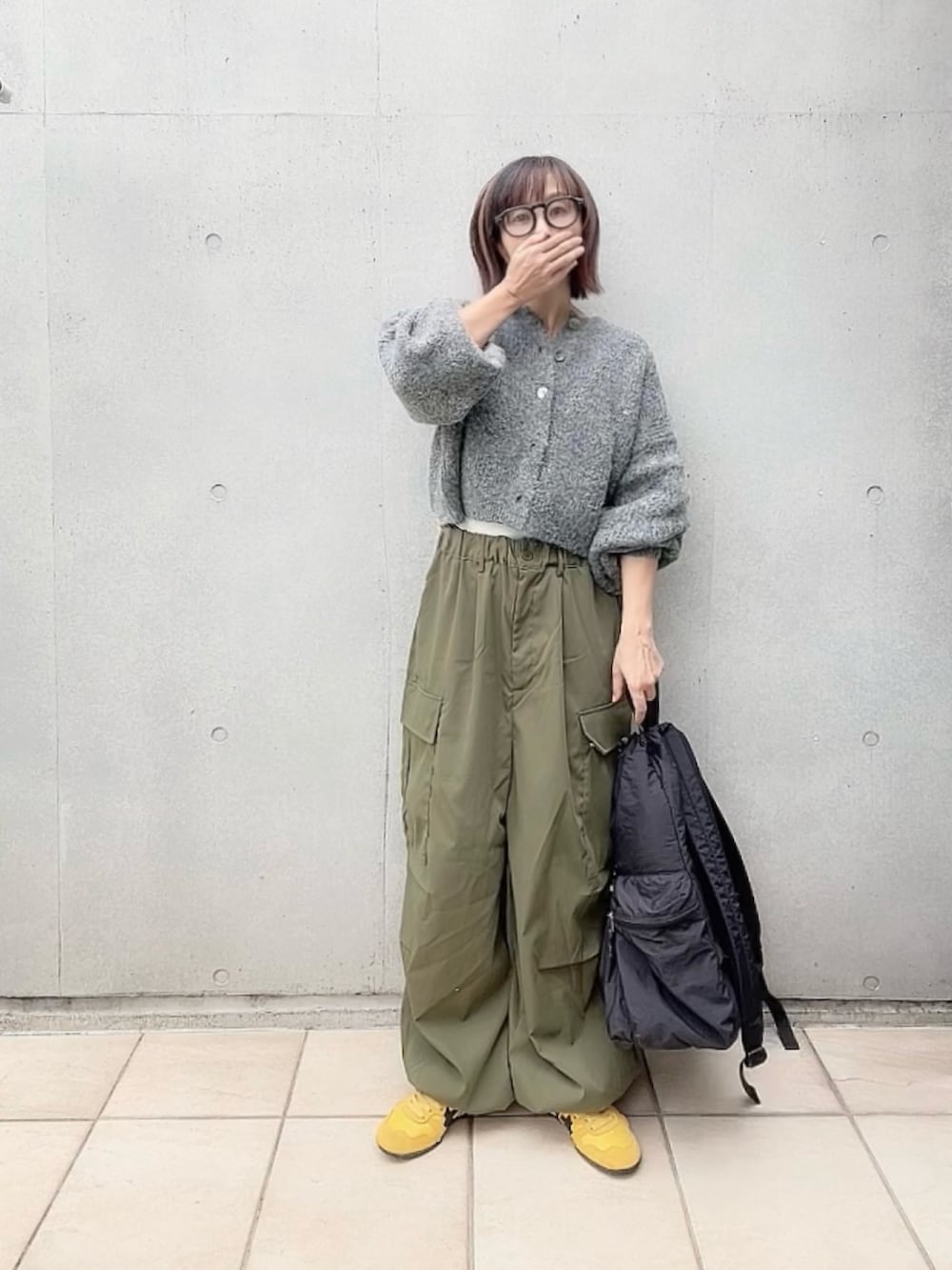 グレー系のカーディガン/ボレロ、ホワイト系のキャミソール、グリーン系のカーゴパンツを着用したレディースの秋コーディネートの2枚目の写真