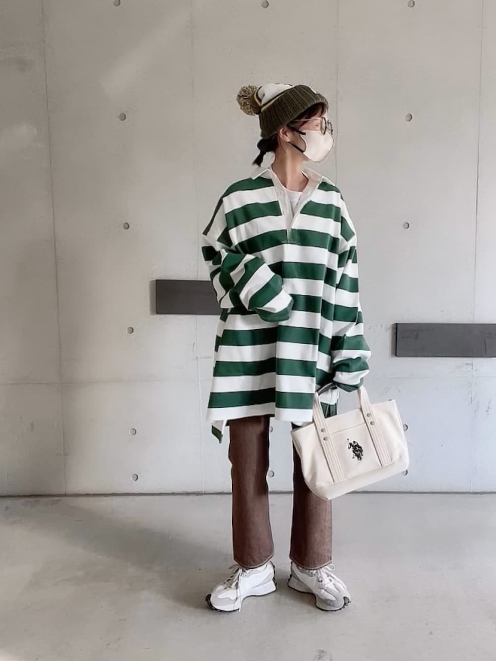 ブラウン系のデニムパンツ、ホワイト系のスニーカー、ホワイト系のトートバッグを着用したレディースの春コーディネートの3枚目の写真