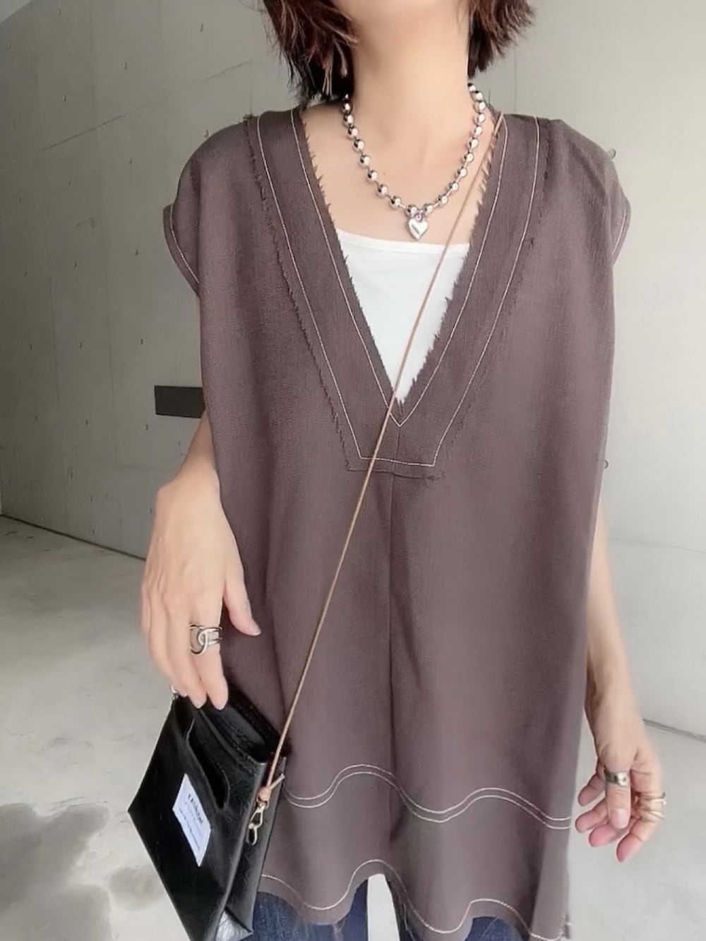 ブラウン系のベスト、ブルー系のデニムパンツ、ブラック系のサンダルを着用したレディースの夏コーディネートの5枚目の写真