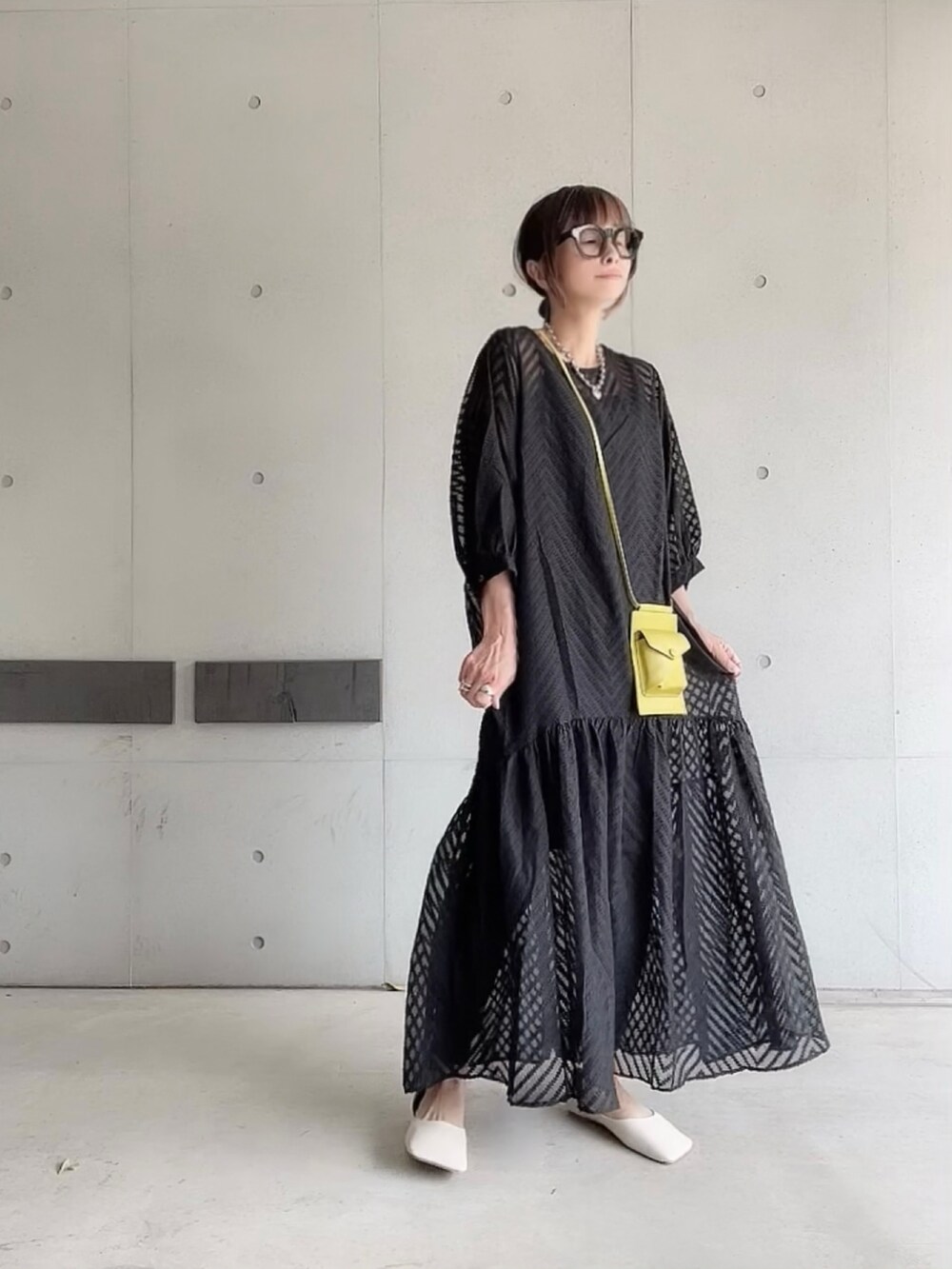 ブラック系のワンピース、グリーン系のショルダーバッグ、ホワイト系のパンプスを着用したレディースの夏コーディネートの3枚目の写真