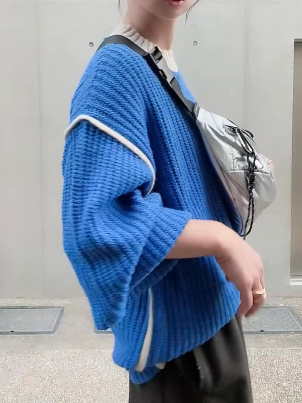 ブルー系のニット/セーター、シルバー系のボディバッグ/ウエストポーチ、ブルー系のスリッポンを着用したレディースの秋コーディネートの4枚目の写真