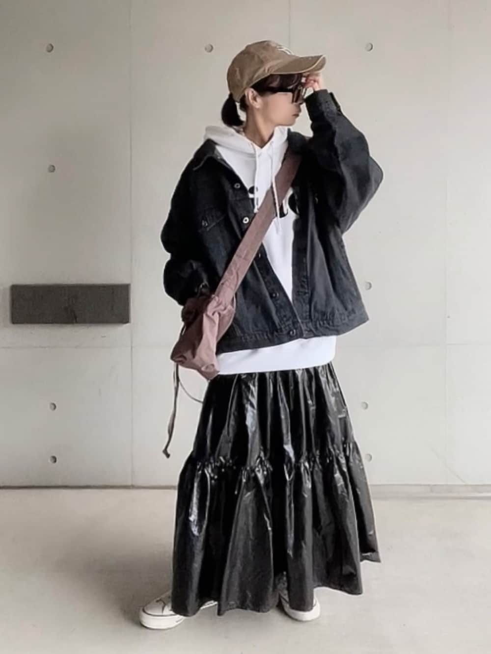ブラック系のデニムジャケット、ホワイト系のパーカー、ブラック系のスカートを着用したレディースの冬コーディネートの2枚目の写真